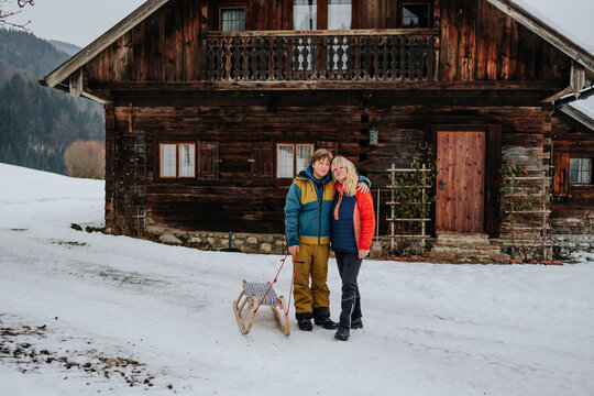 grandmother and grandson posing with sled in front of alpine cab