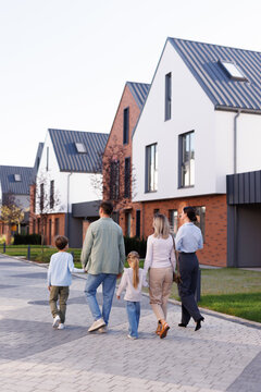 Back view of female realtor showing townhouse complex to young family