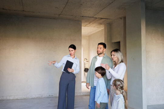 Realtor showing and pointing in new empty house inside to family