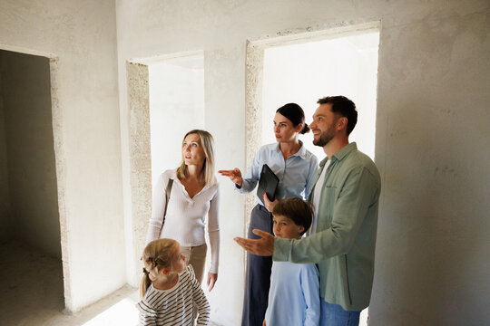 Serious female realtor showing new empty house inside to young family