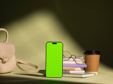 Aesthetic arrangement of a smartphone, books, glasses, and coffee cup