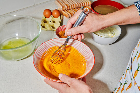 a man mixing egg yolks and sugar with a whisk
