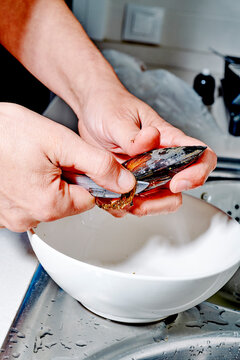 a man removes the beard from a fresh mussel