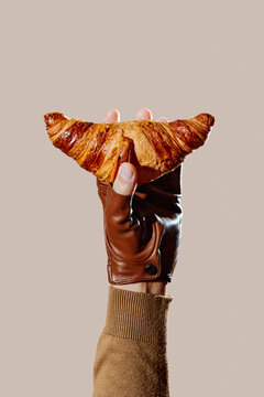 a croissant is lifted in the air by a gloved hand