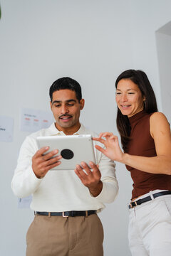 Colleagues examine work tasks as they look at the tablet