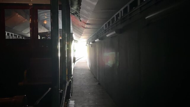 The view from inside a vintage train shows a dark tunnel ahead with light at the exit. The image symbolizes travel, movement, and journey concepts.