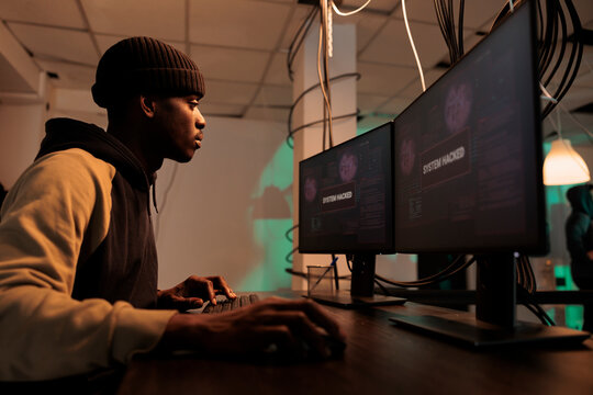 African american thief working with encryption to hack computer system, hacking network to steal database information. Male spy breaking into government server, planting trojan virus.