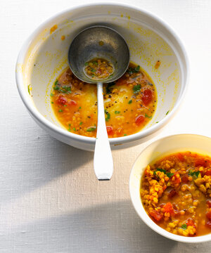 Bowl with leftovers from a lentil dal serving spoon on a white table