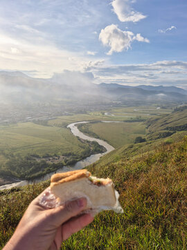 Person enjoying a snack on top of a mountain