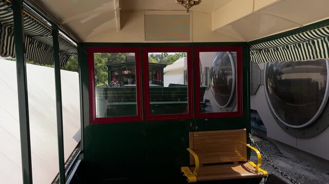 An empty vintage train car interior features wooden seating and green painted walls. The image highlights classic railway design and historic transportation.