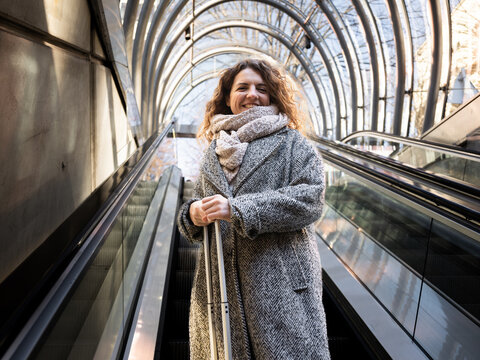 Woman traveling walking up escalator with suitcase