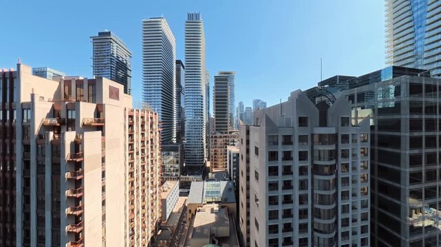 Toronto Aerial view of modern urban cityscape featuring residential apartment buildings and commercial high-rise towers under clear blue sky