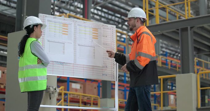 Rail engineers engaged in a planning and review session, focusing on a board displaying schedules, maintenance plans, and performance data of the rail systems. Ensuring efficient rail operations.