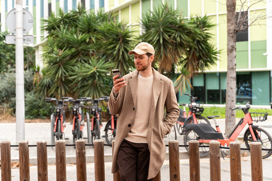Man Checking Phone Near Bike Rental Station 