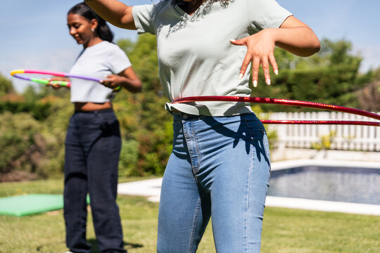 Women enjoying hula hooping in a sunny outdoor garden