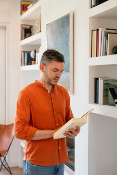 Man reading book in a modern room with bookshelves