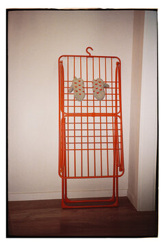 Bright orange rack stands against a white wall with gray gloves