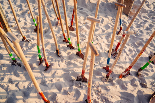Shovels stand upright on sand at a beach during sunset