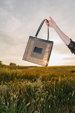 Handbag Held Aloft In Golden Sunset Field