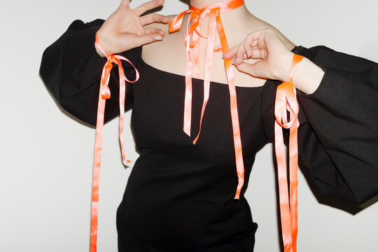 Person wearing a fashion style dress with pink silk ribbon bow 