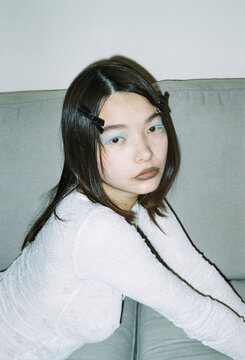 Young Woman With Long Hair Sitting on a Couch in a Simple Room