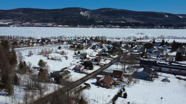 A drone glides over the snowy village of Lac-au-Saumon, revealing its frozen lake and the Appalachian mountains beyond. Filmed in 2026 in Quebec&rsquo;s scenic Matapedia Valley.