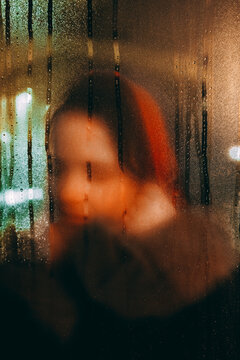 Woman touching a foggy window in the evening