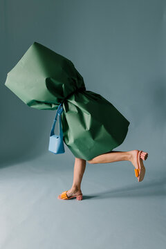 Green Wrapped Figure Wearing Colorful Sandals in Studio