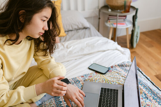 Checking Smartwatch Using Laptop on Bed