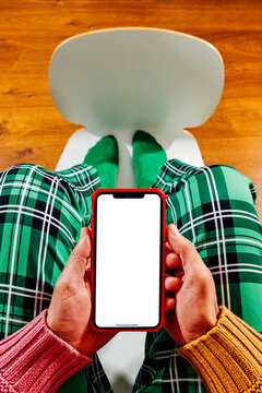 both hands holding a smartphone between bent knees