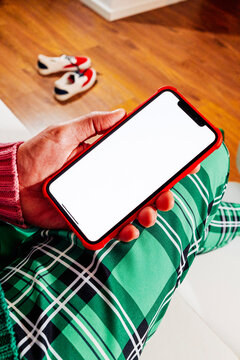 a smartphone with a blank screen over green plaid trousers