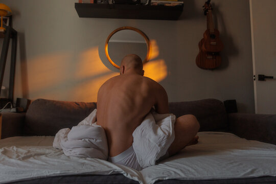Person Sitting on Bed in Room With Soft Light in Morning
