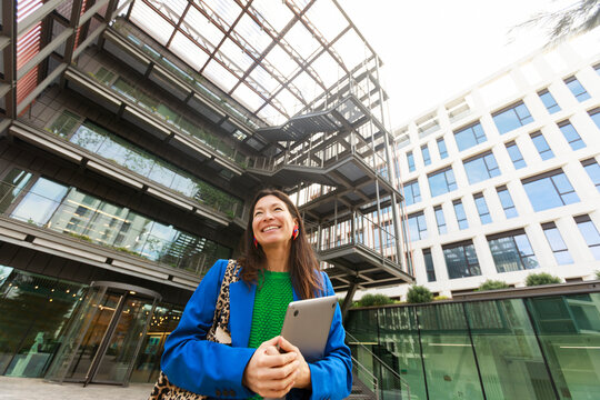 Woman With Tablet Stands Outside Modern Building 