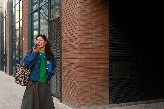 Woman in Green Sweater Enjoys Snack Near Modern Building