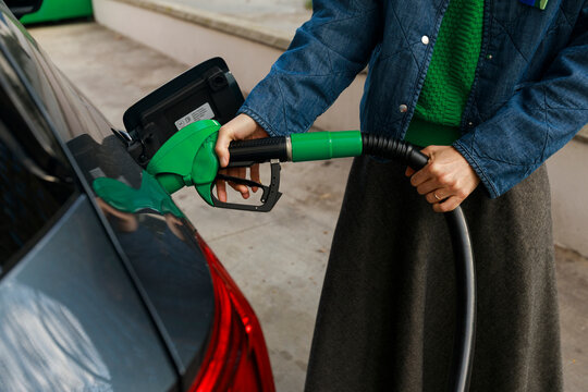 woman Fills Car With Fuel at Gas Station in Urban Area