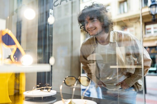 Smiling man window shopping for new sunglasses