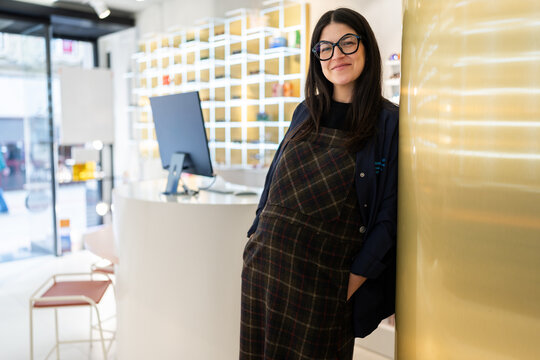 Pregnant optometrist smiling in modern optometry clinic