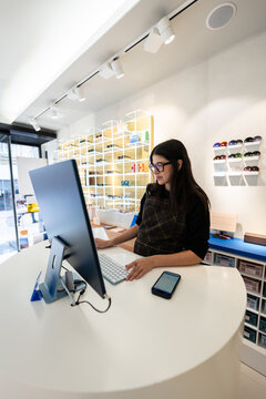 Pregnant optometrist working on computer in optical shop