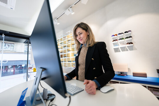 Woman optician working on computer in optical shop