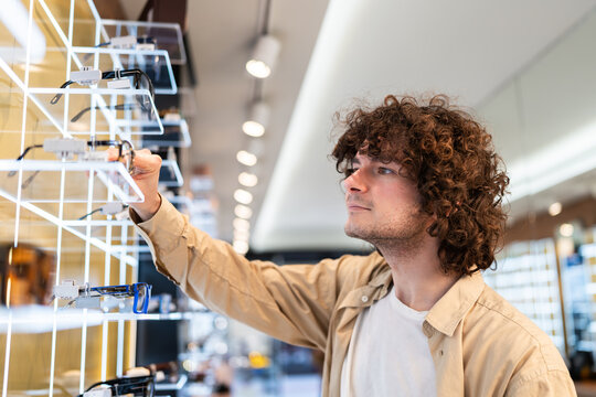 Young man choosing new eyewear in optical shop