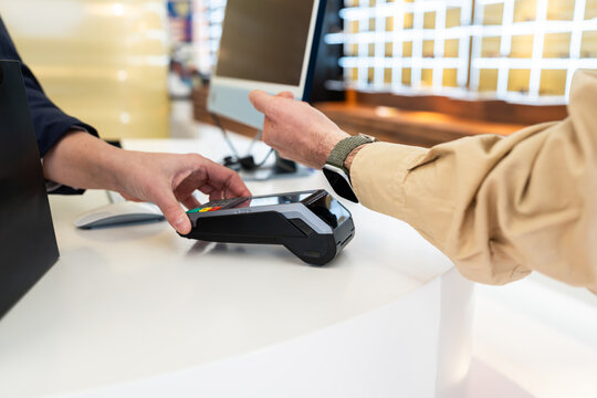 Client paying contactless with smartwatch in optical shop