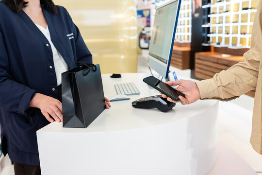 Customer paying with smartphone using pos terminal in optical shop