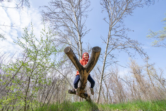 Child climbs a log in the forest