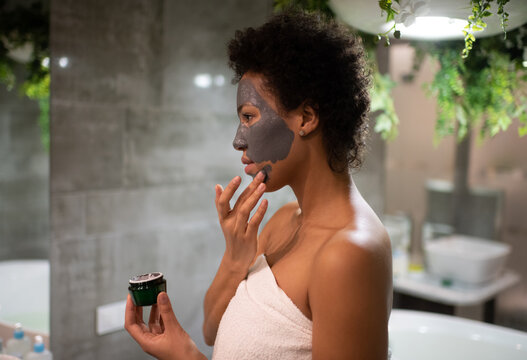 African American woman smearing clay mask