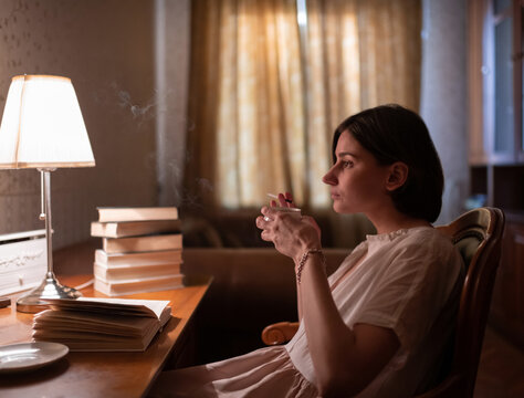 Woman with hot drink and cigarette resting with books