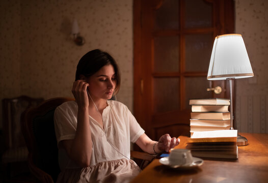 Young woman reader using smartphone and listening to music