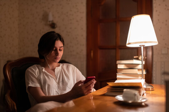 Female bookworm listening to music and browsing smartphone
