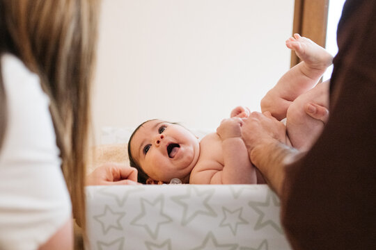 Parents caring for baby on changing table at home