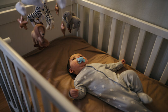 Baby lying in crib looking at mobile