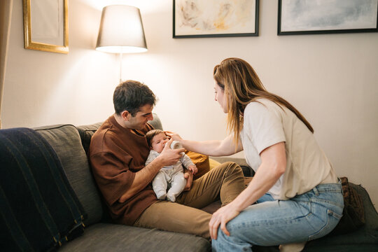 Parents gently feeding baby bottle at home
